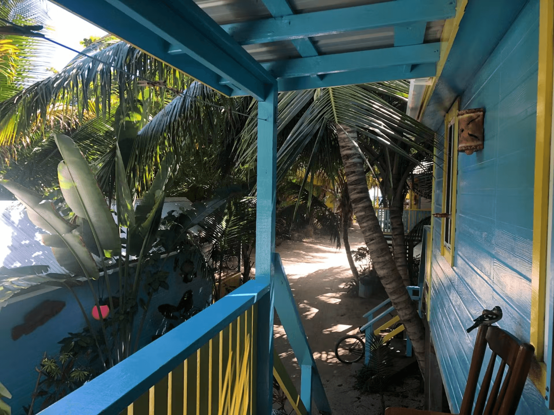 View from balcony overlooking palm trees and stairs leading to sand-covered ground