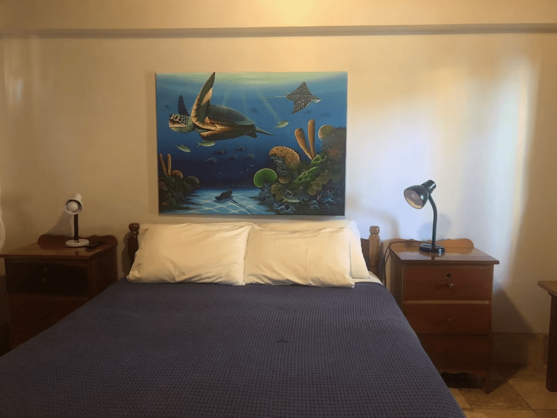 Queen bed with tropical coral reef artwork, nightstands with table lamps