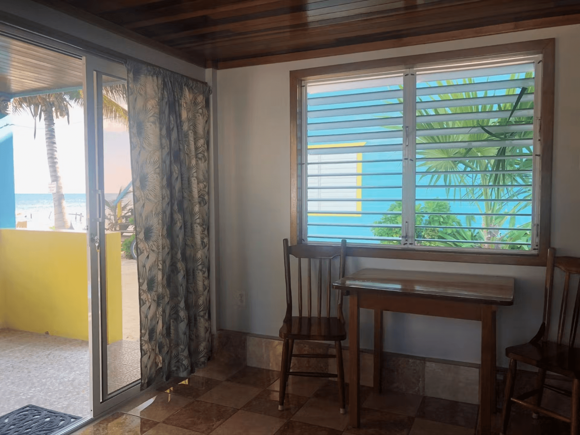 Kitchen table with chairs under window and sliding glass doors leading to patio