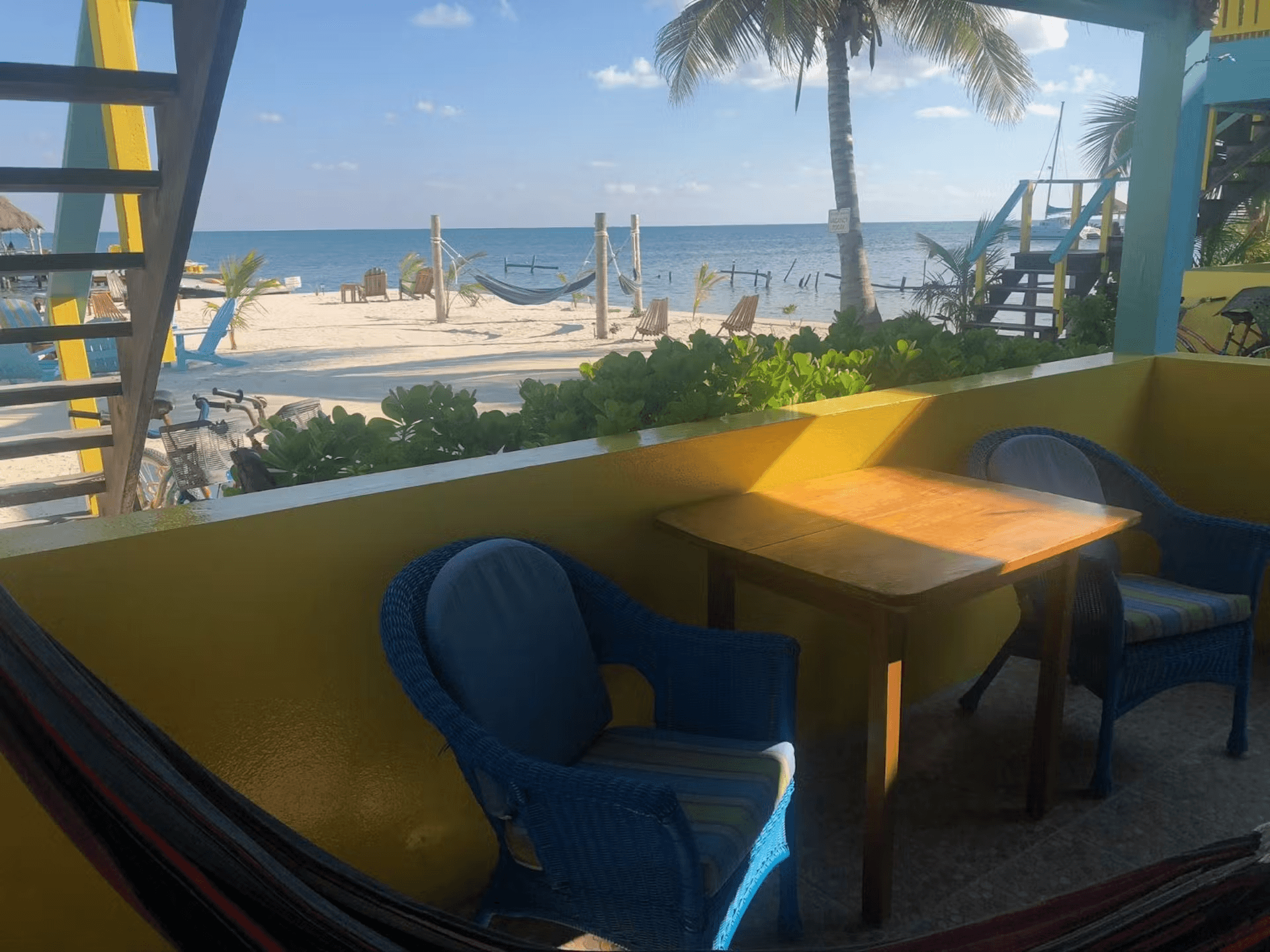 Patio with wicker chairs, table and hammock and views of beach and ocean behind