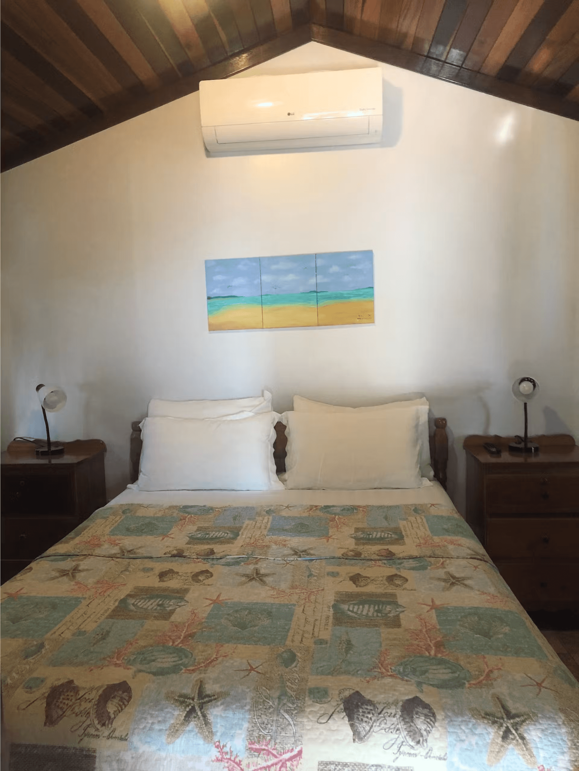 Queen bed with bedding featuring a pastel seashell design, two side tables with lamps