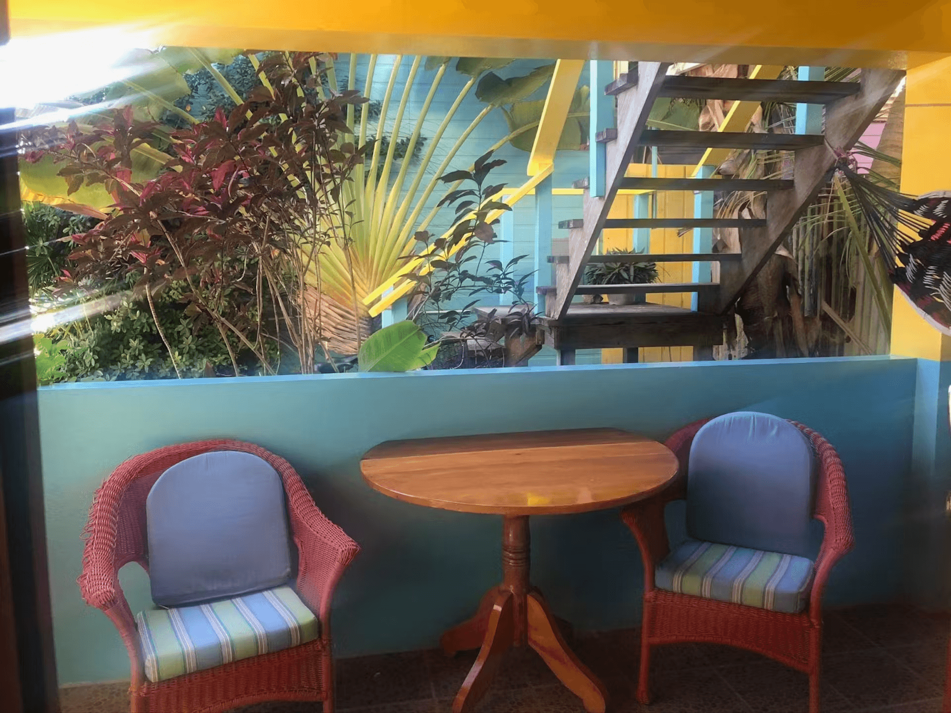 Patio with two chairs and a table and lush tropical foliage behind