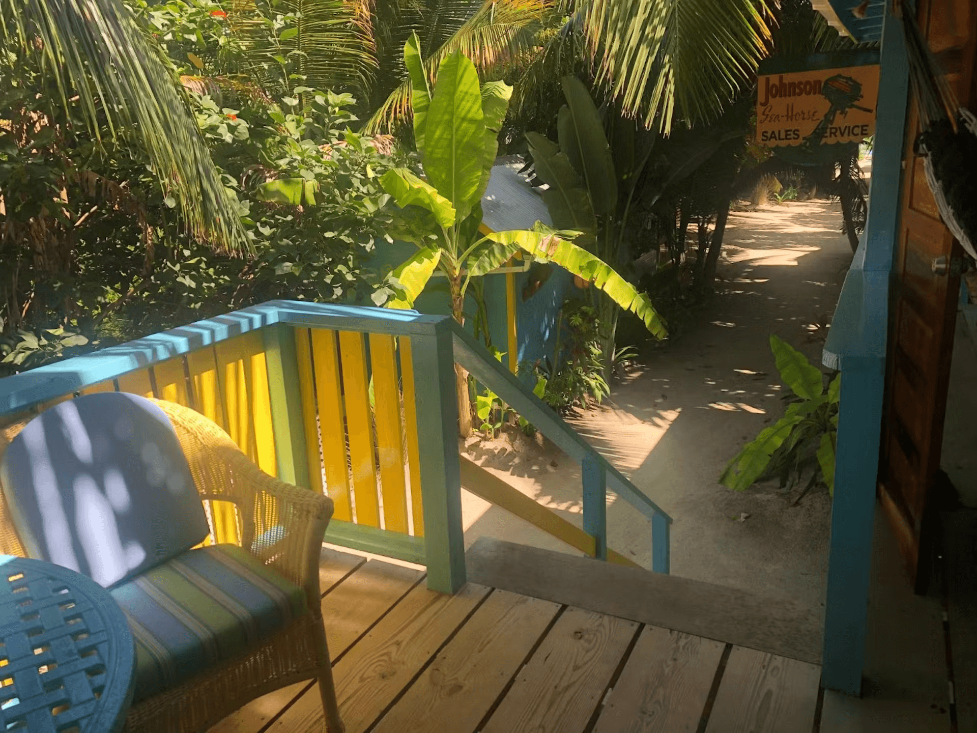 View from balcony looking down stairs at sandy walkway and tropical foliage
