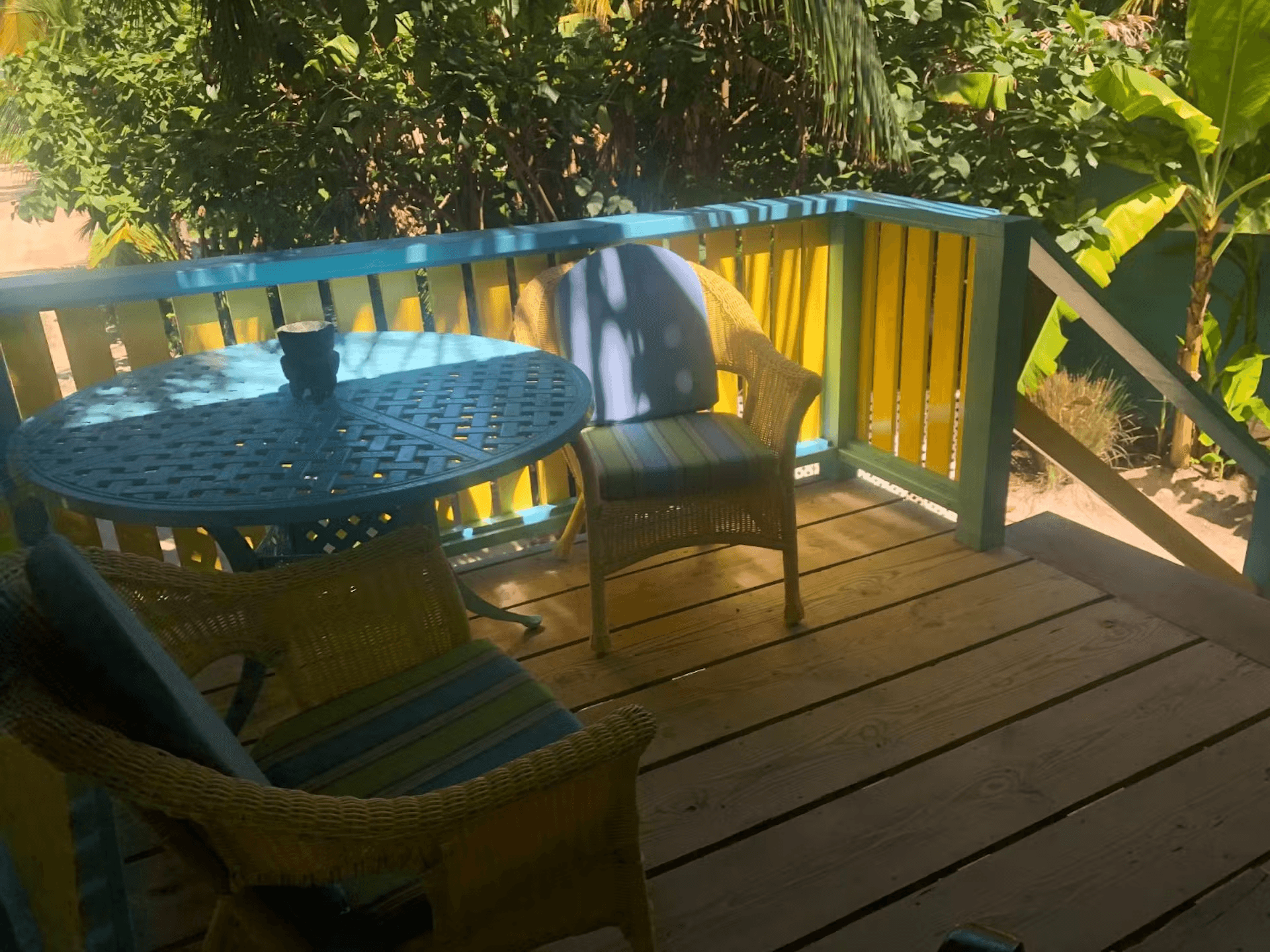 Balcony with yellow and blue railing and complementary set of two chairs with round table between