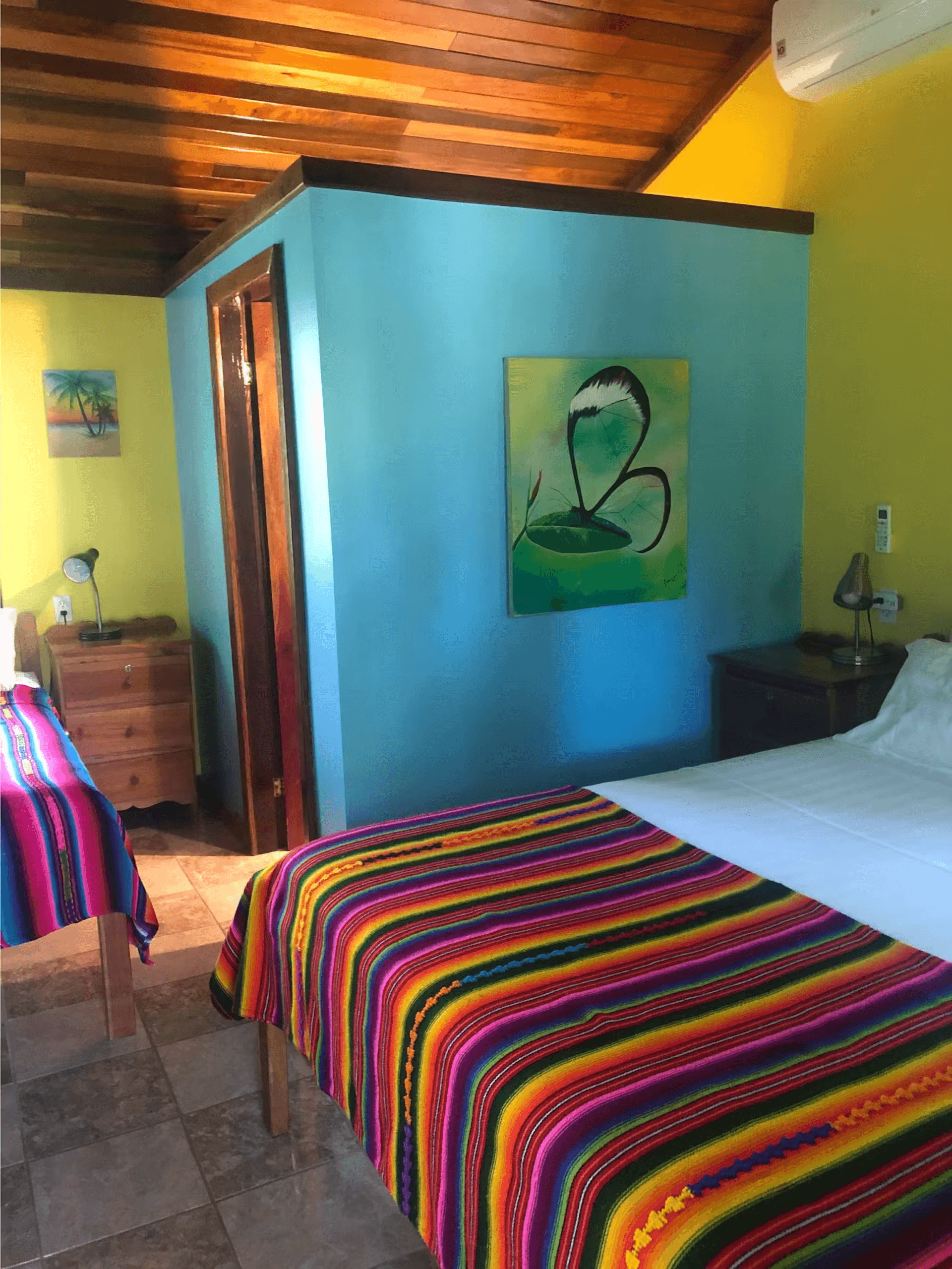 Blue and yellow painted bedroom with queen bed, dresser, nightstand, and richly finished wood ceiling