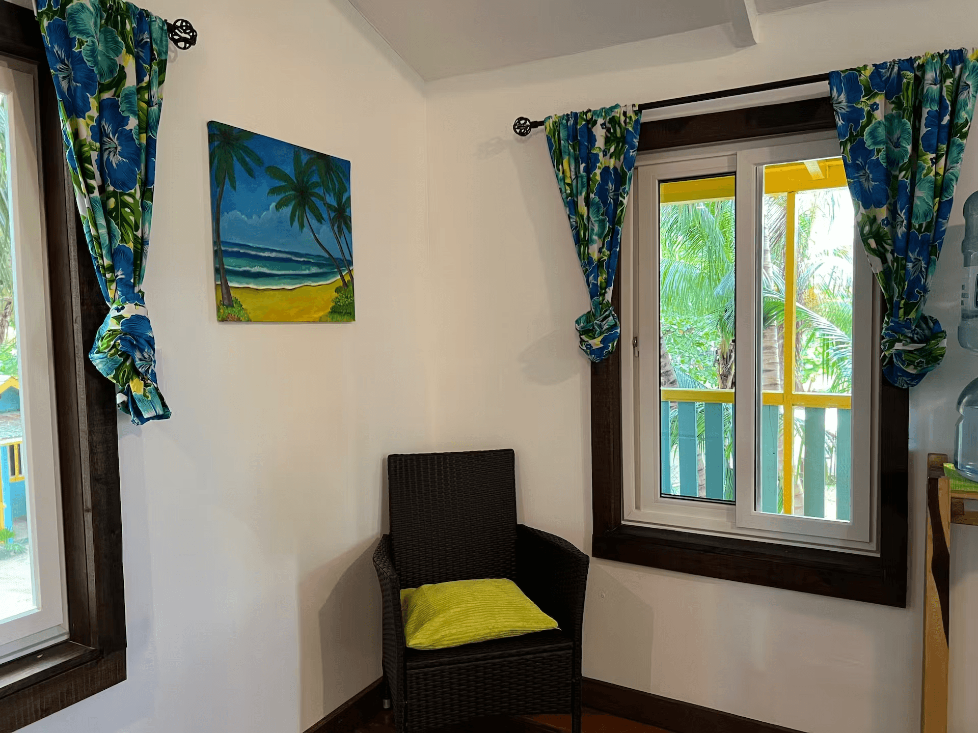 Cozy chair in corner with beach-themed artwork and sunny windows on both sides