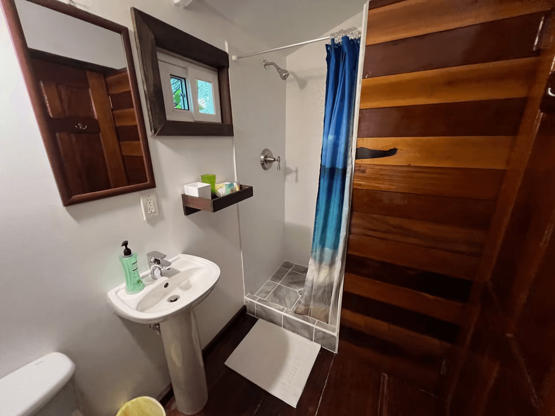 Bathroom with pedestal sink, walk-in shower, and Belizean hardwood accents