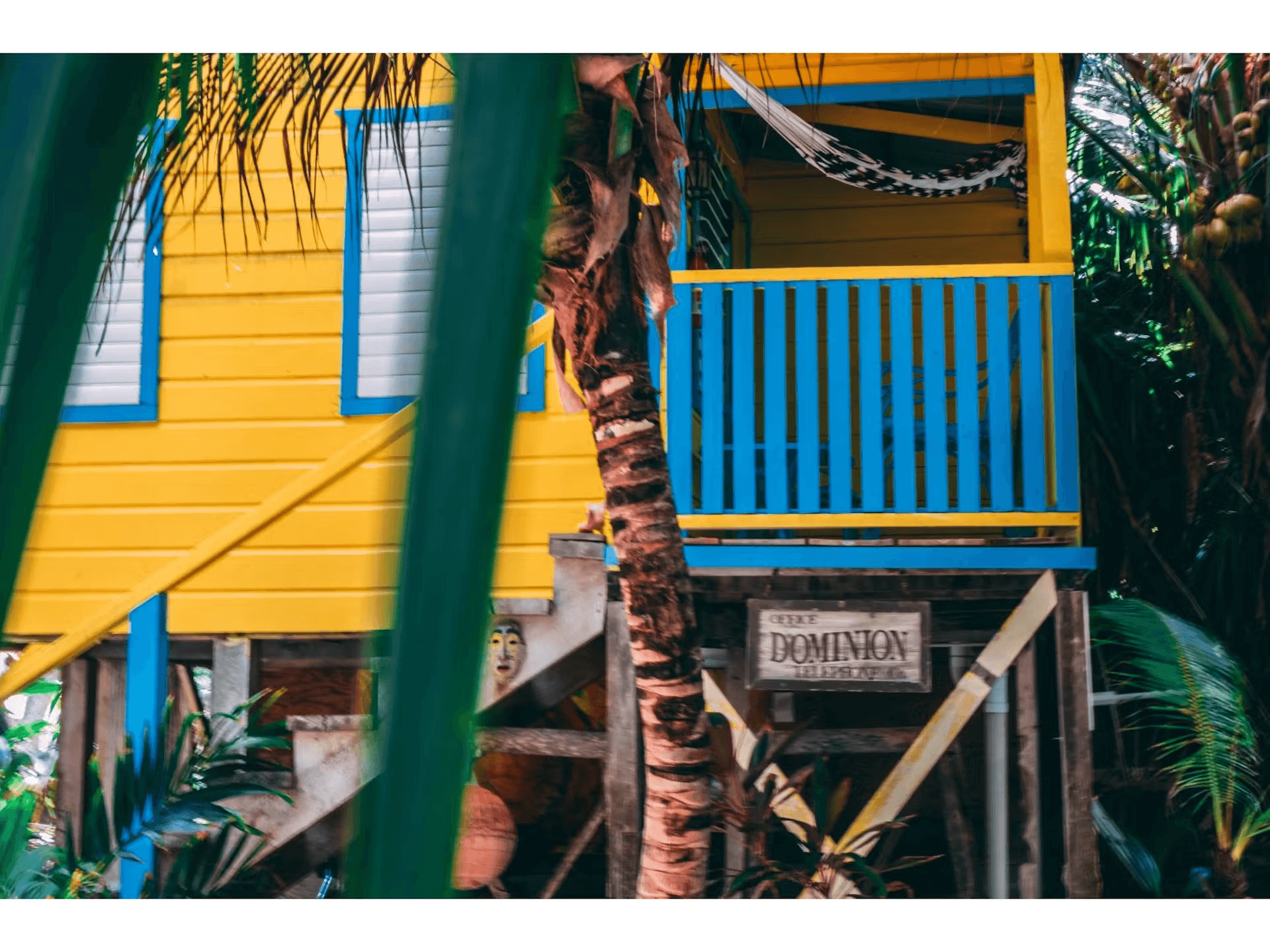 Brightly painted blue and yellow cabana with stairs leading to balcony
