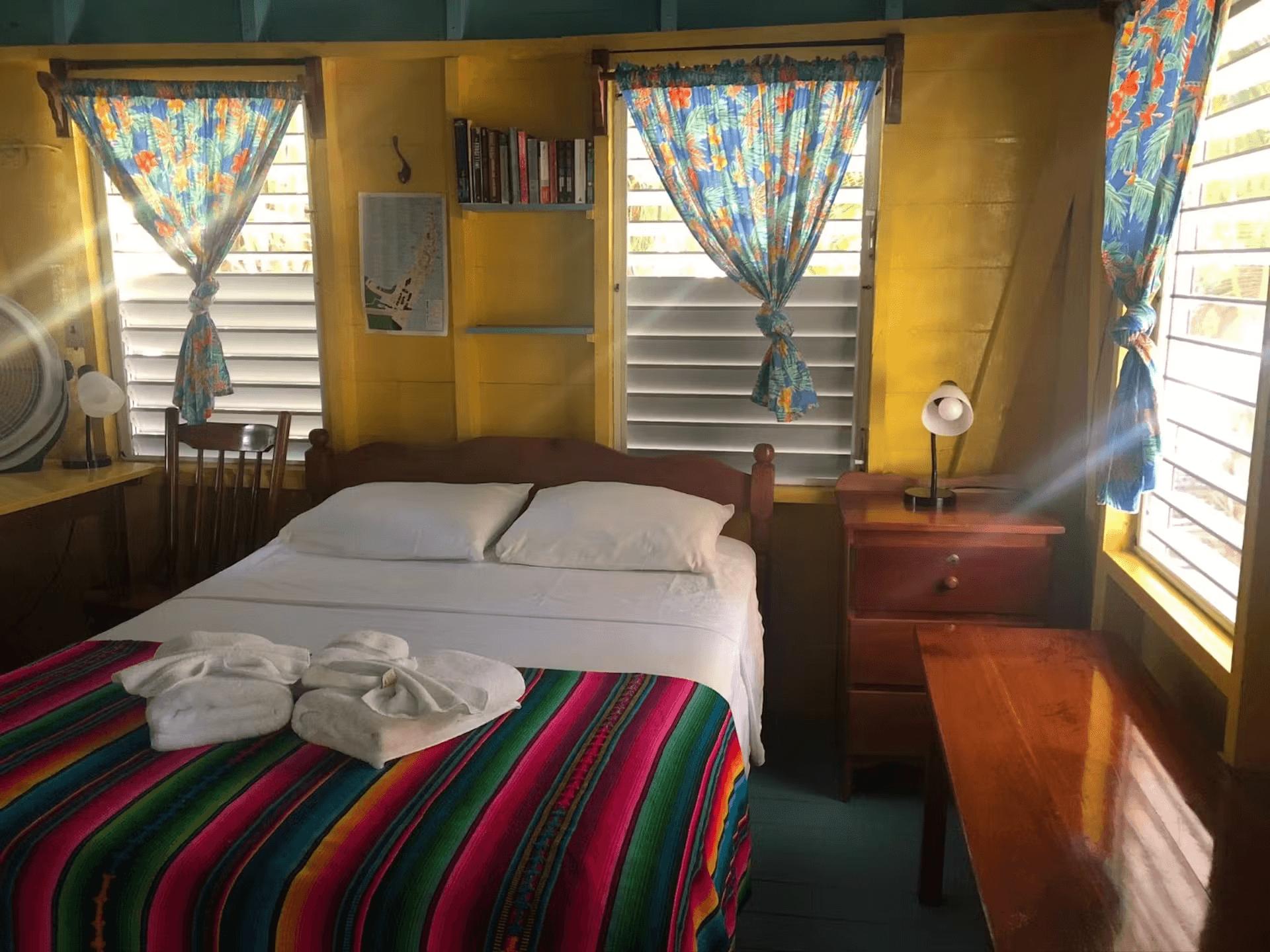 Bedroom with double bed, rich wooden furniture and sunny windows with blinds and curtains