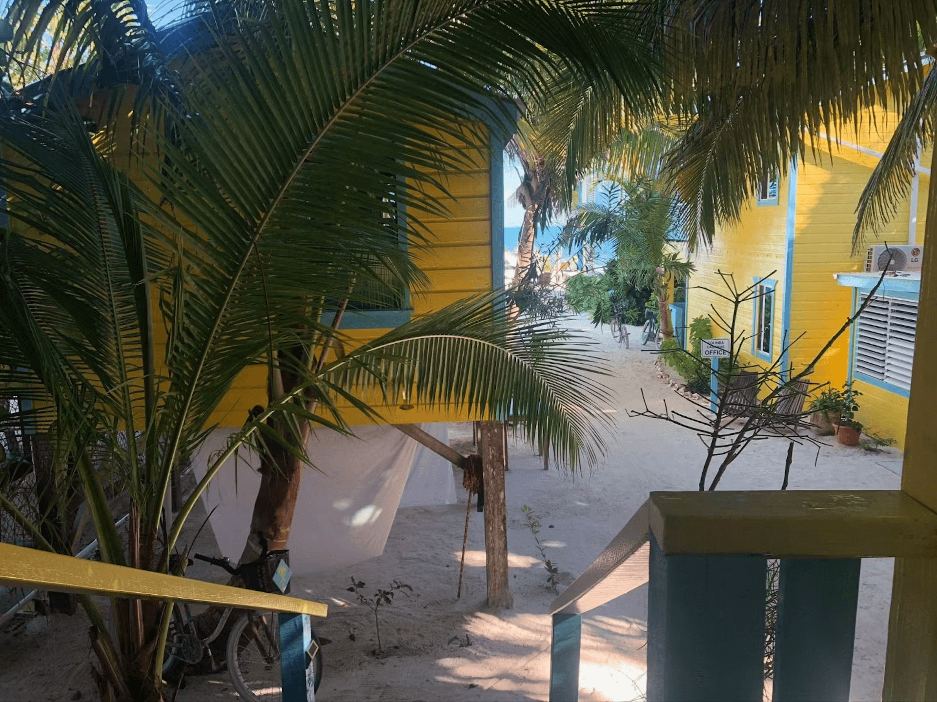 View of palm trees and neighboring cabanas from balcony at top of stairs