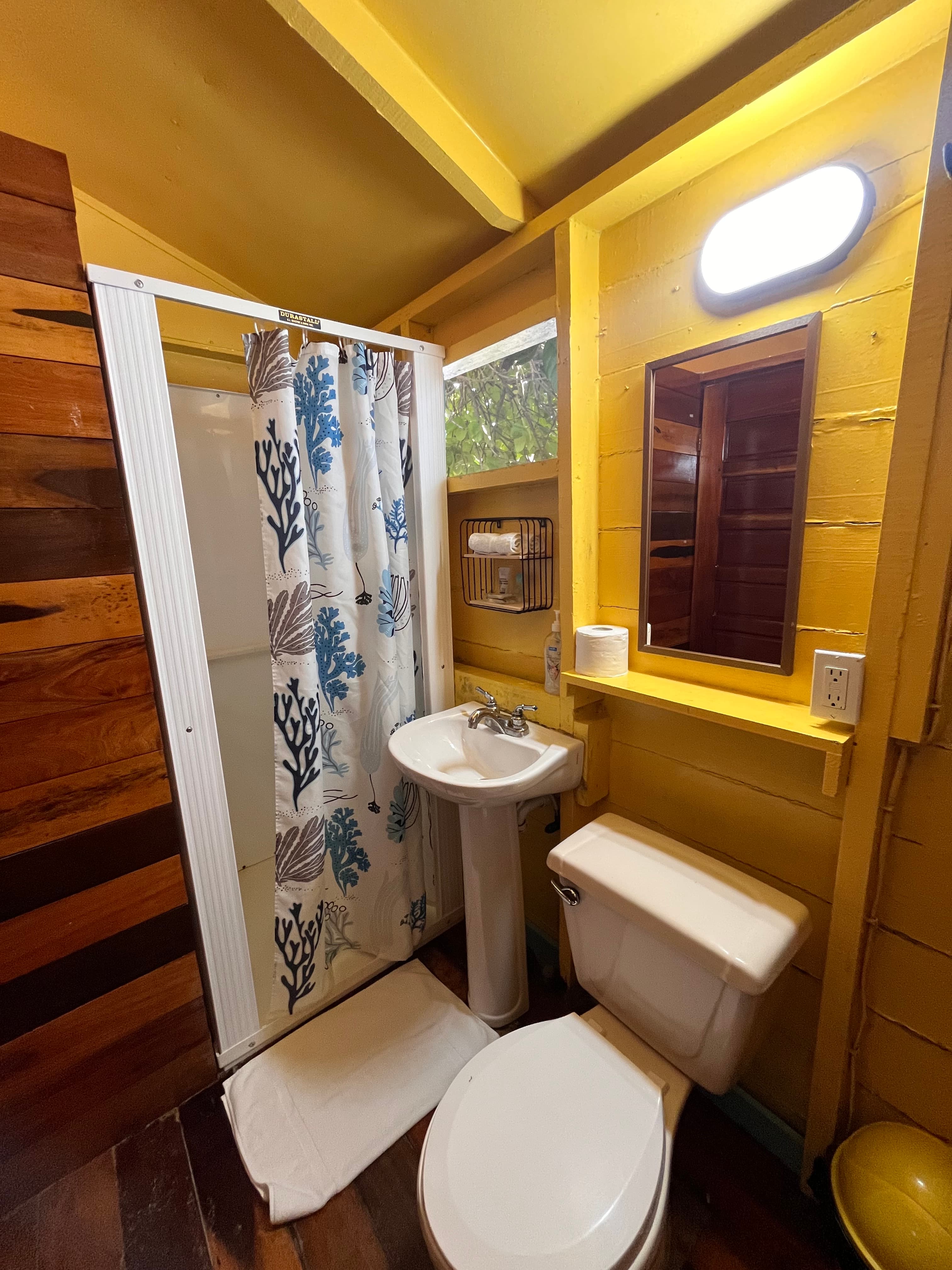 Brightly colored bathroom featuring a shower, sink, and toilet.