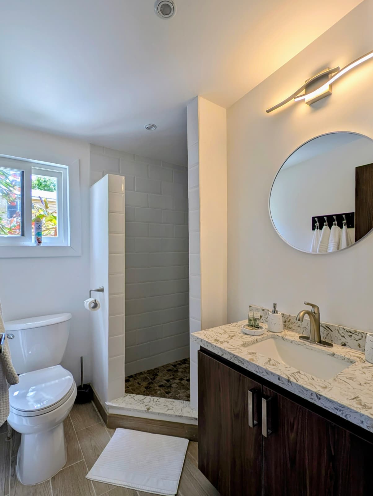 Modern bathroom featuring a shower, toilet, and a stylish vanity with a circular mirror.
