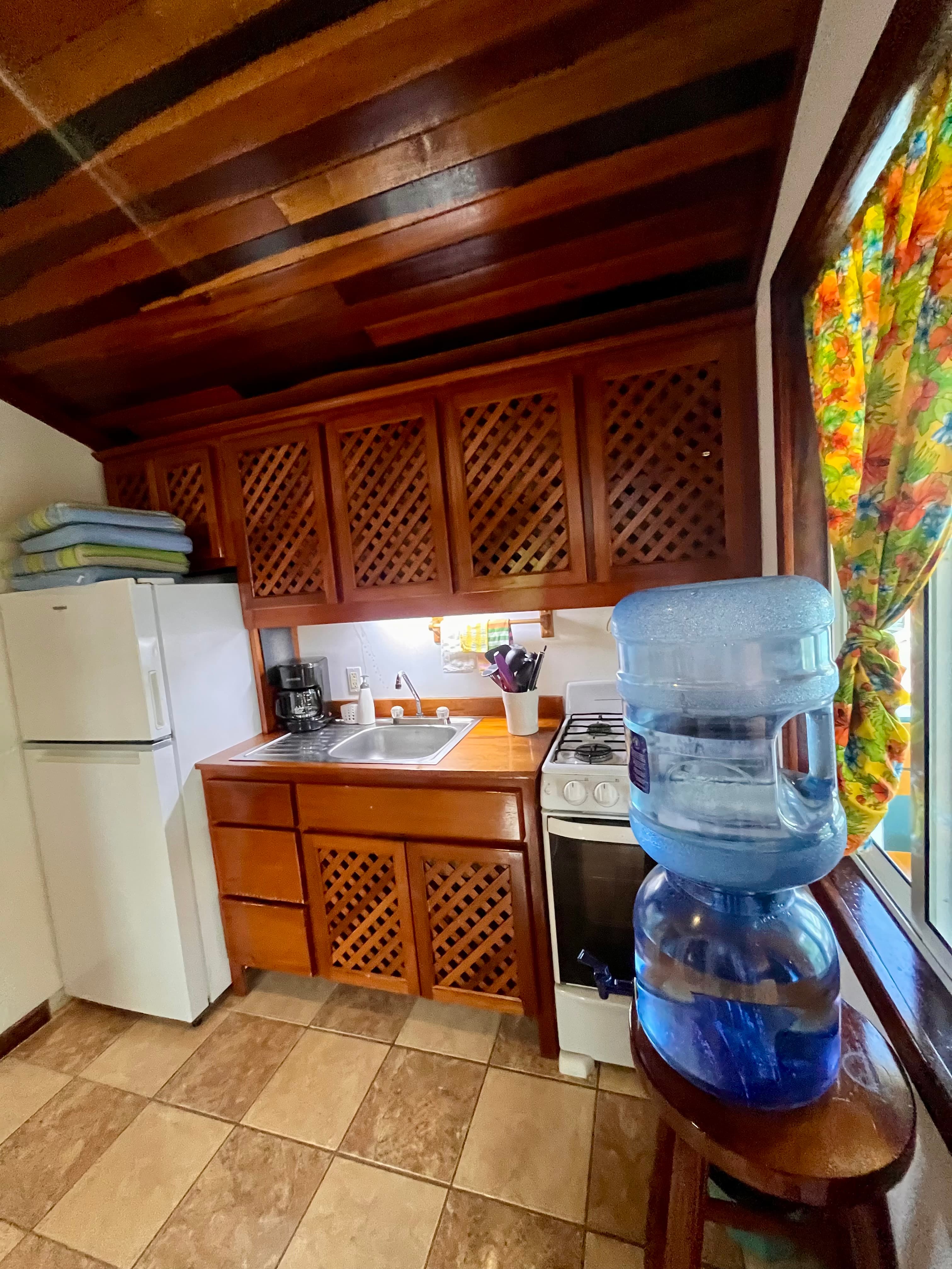 A cozy kitchen featuring wooden cabinets, a sink, a stove, and a water dispenser.