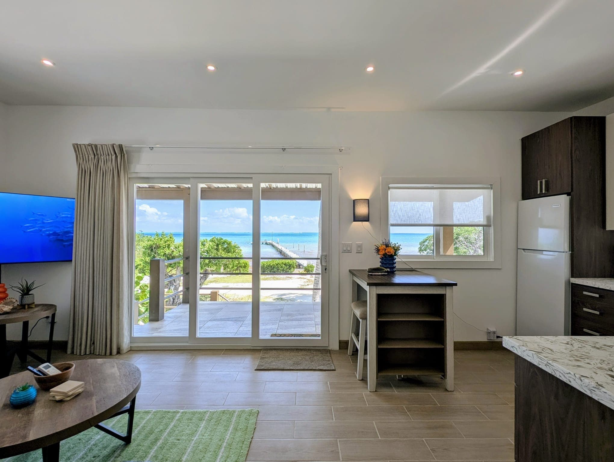 Bright and airy interior of a coastal apartment with sliding glass doors overlooking the ocean.