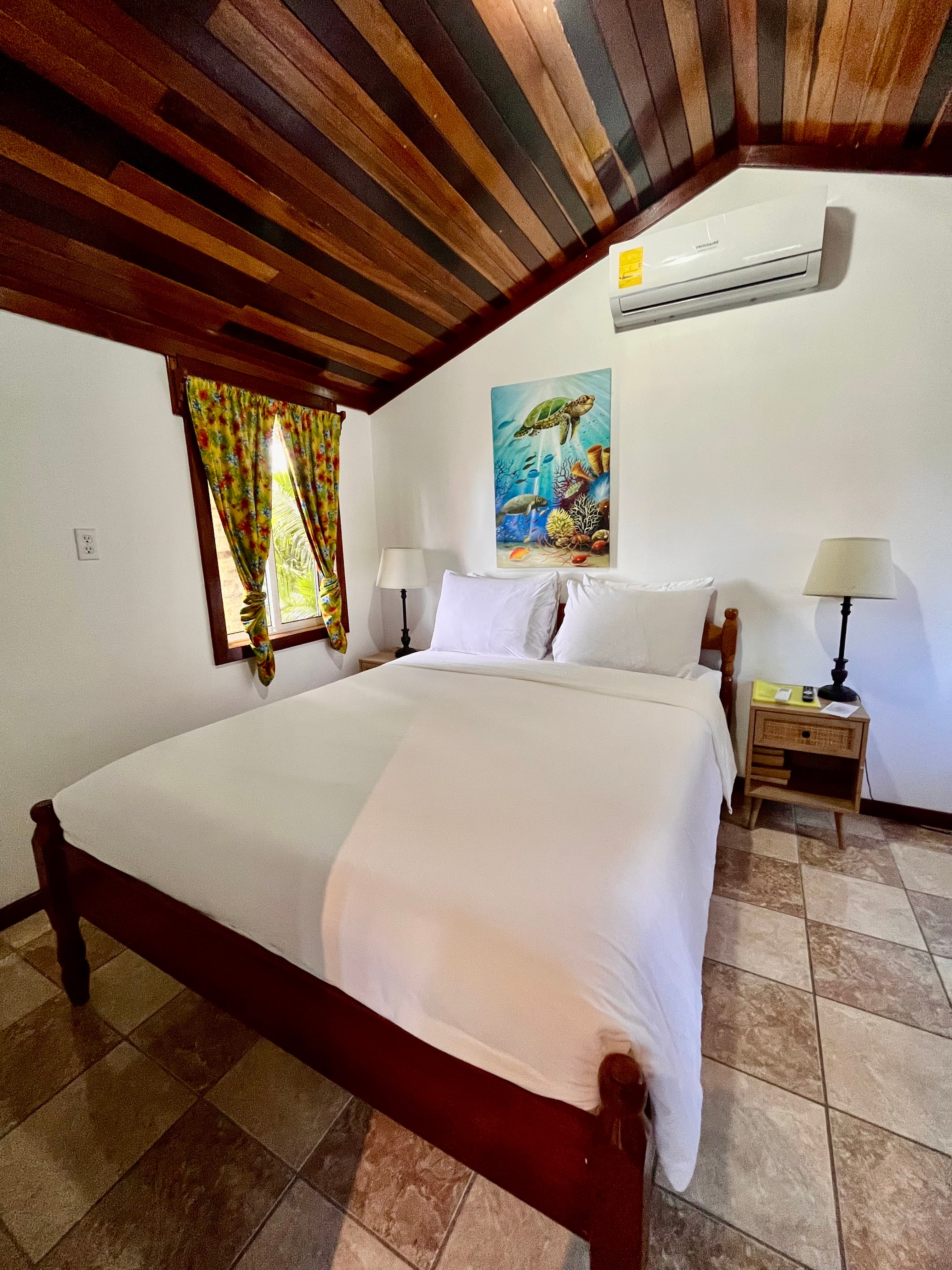 Cozy bedroom featuring a wooden ceiling, double bed, and decorative curtains.
