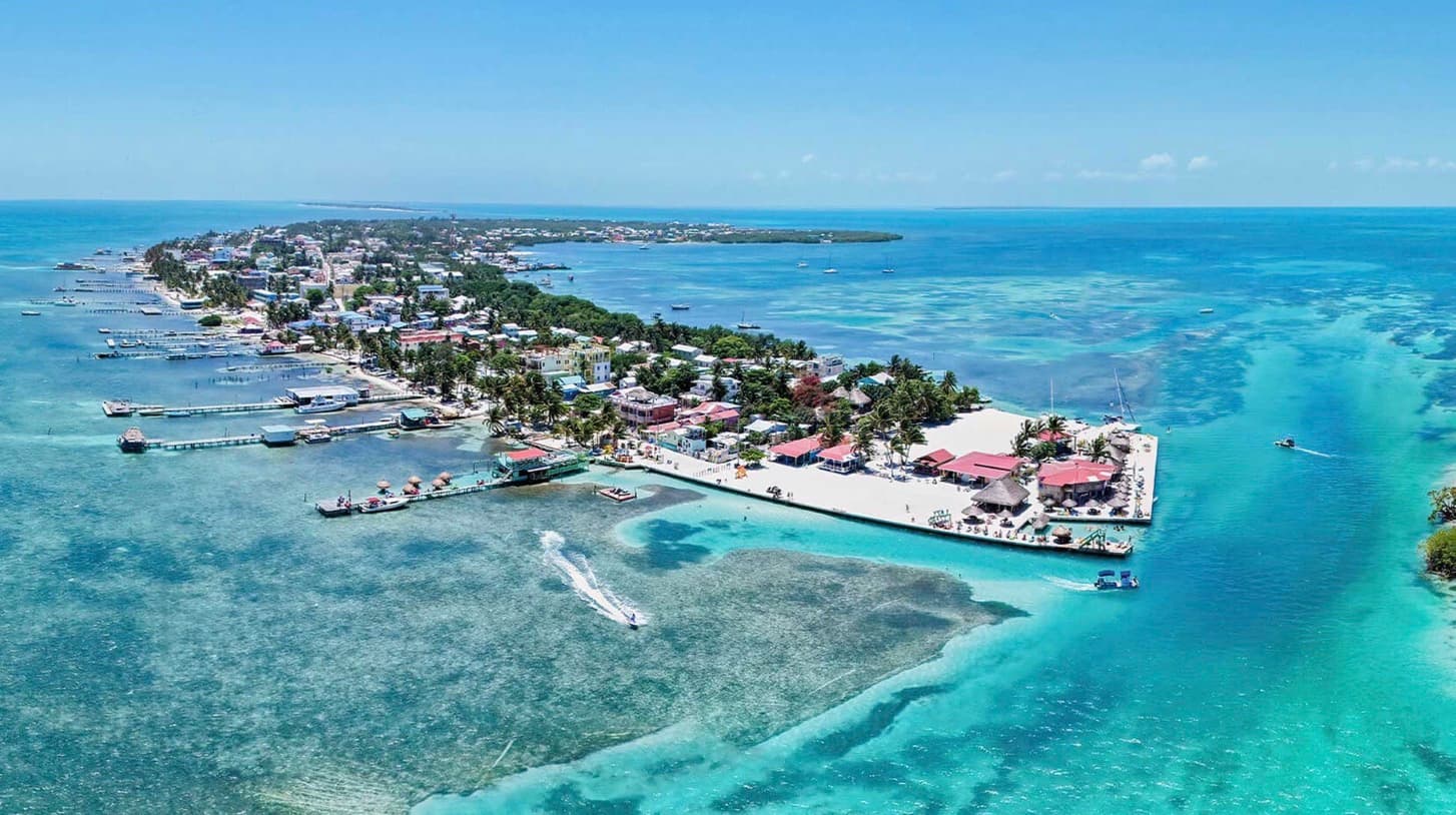Aerial view of a tropical island with vibrant blue waters, lush greenery, and coastal buildings.