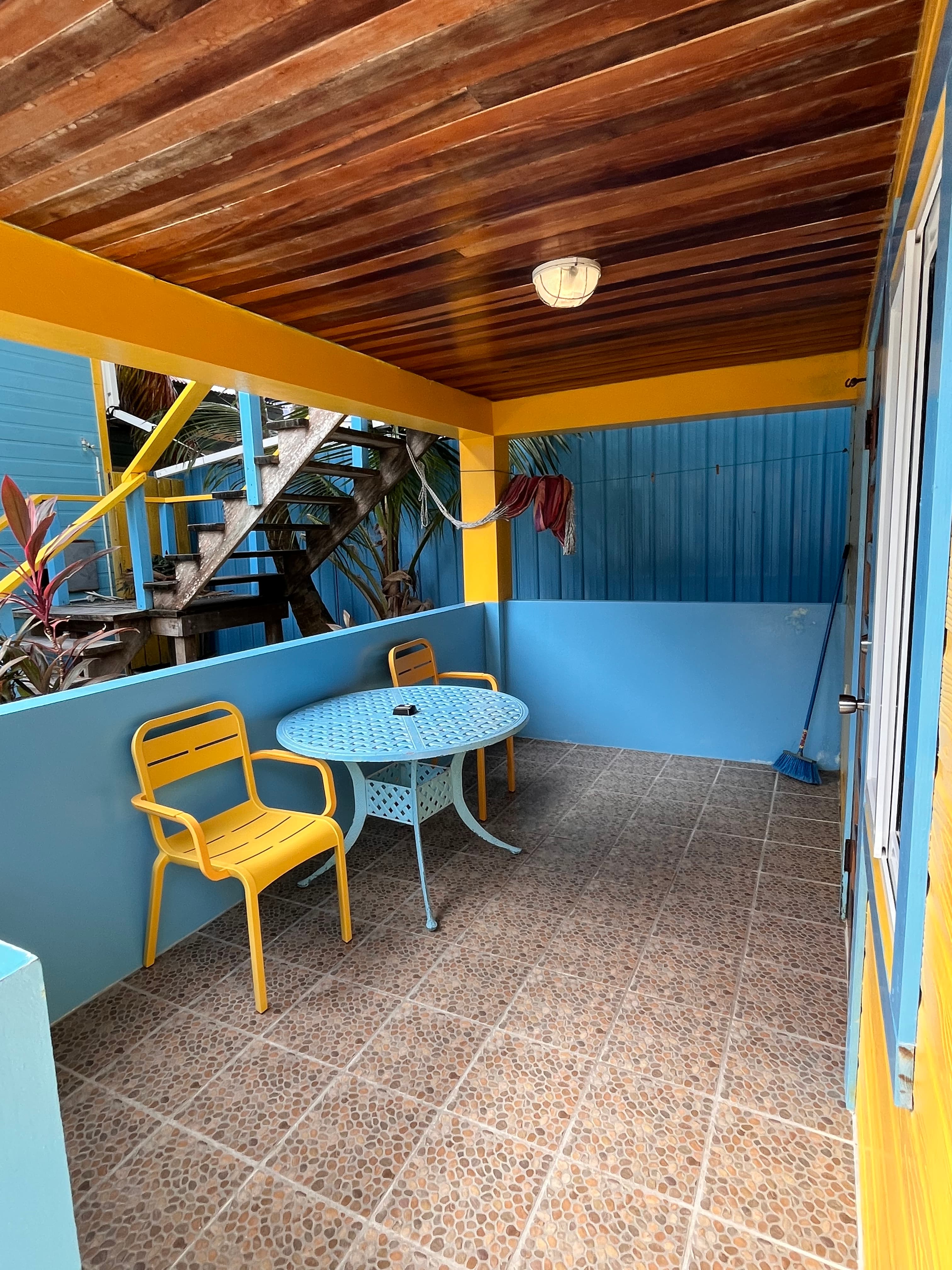 A vibrant outdoor seating area featuring a yellow table and chairs against a blue background.