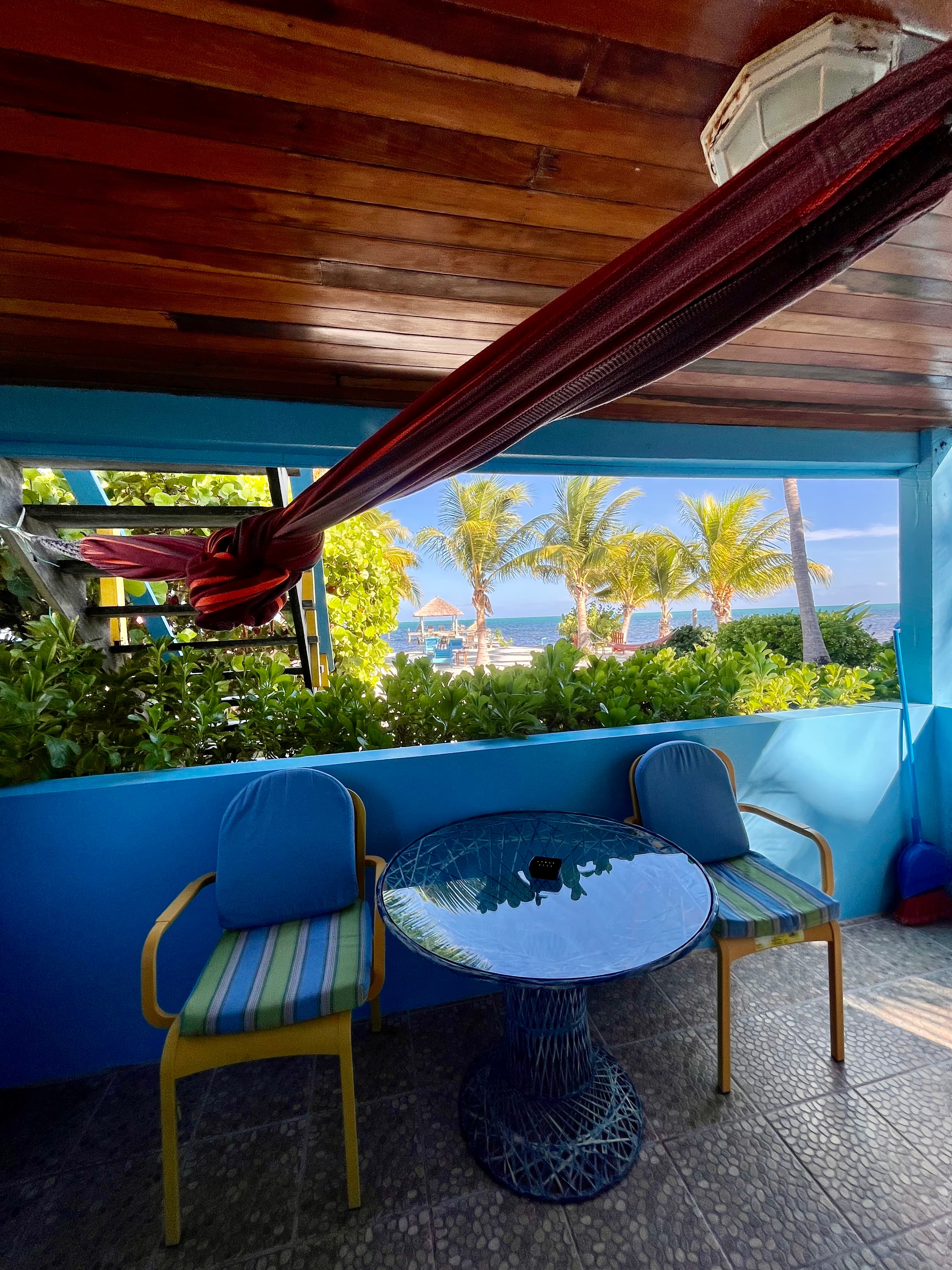 A cozy outdoor seating area with a view of palm trees and the ocean.