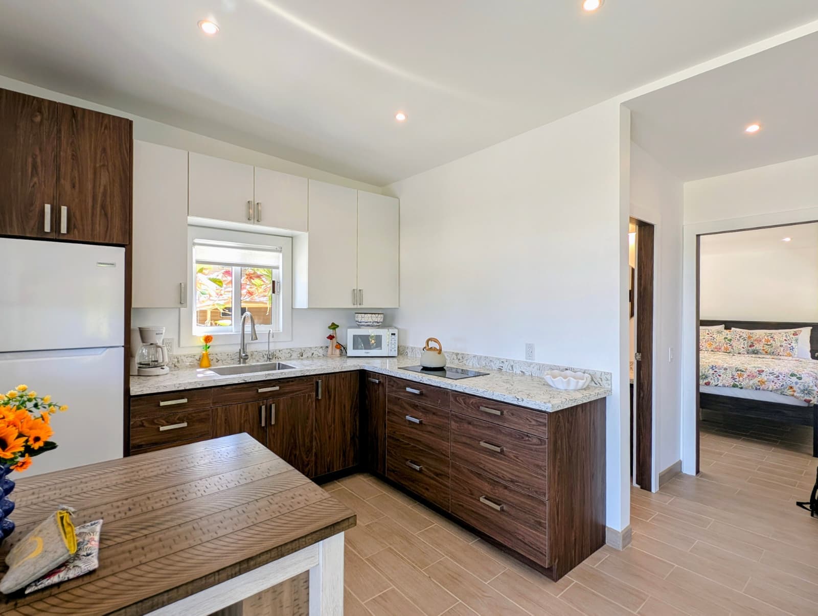 Modern kitchen featuring wooden cabinets, granite countertops, and a view into a nearby bedroom.