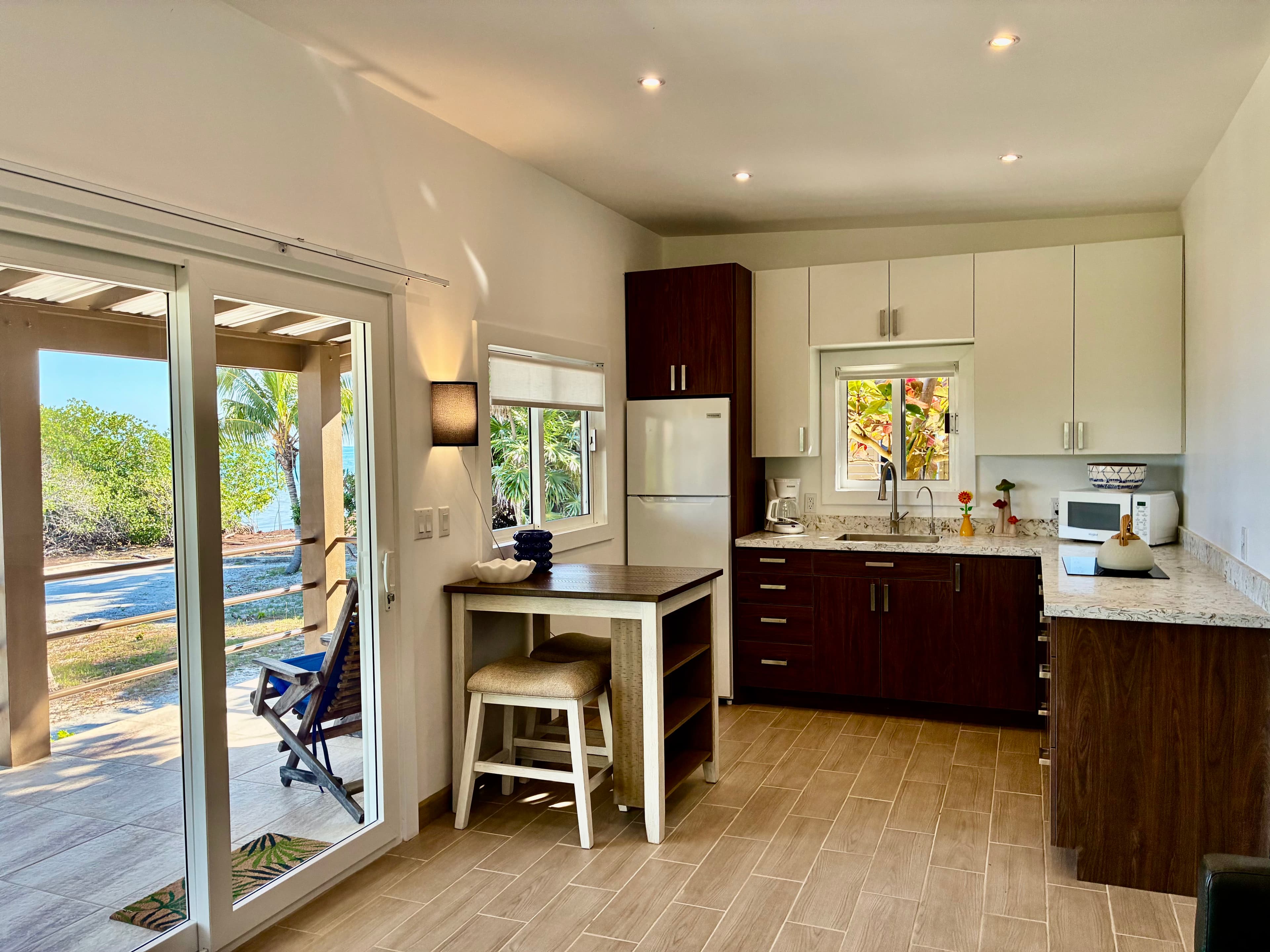 Bright and modern kitchen with a view of a patio and trees outside.
