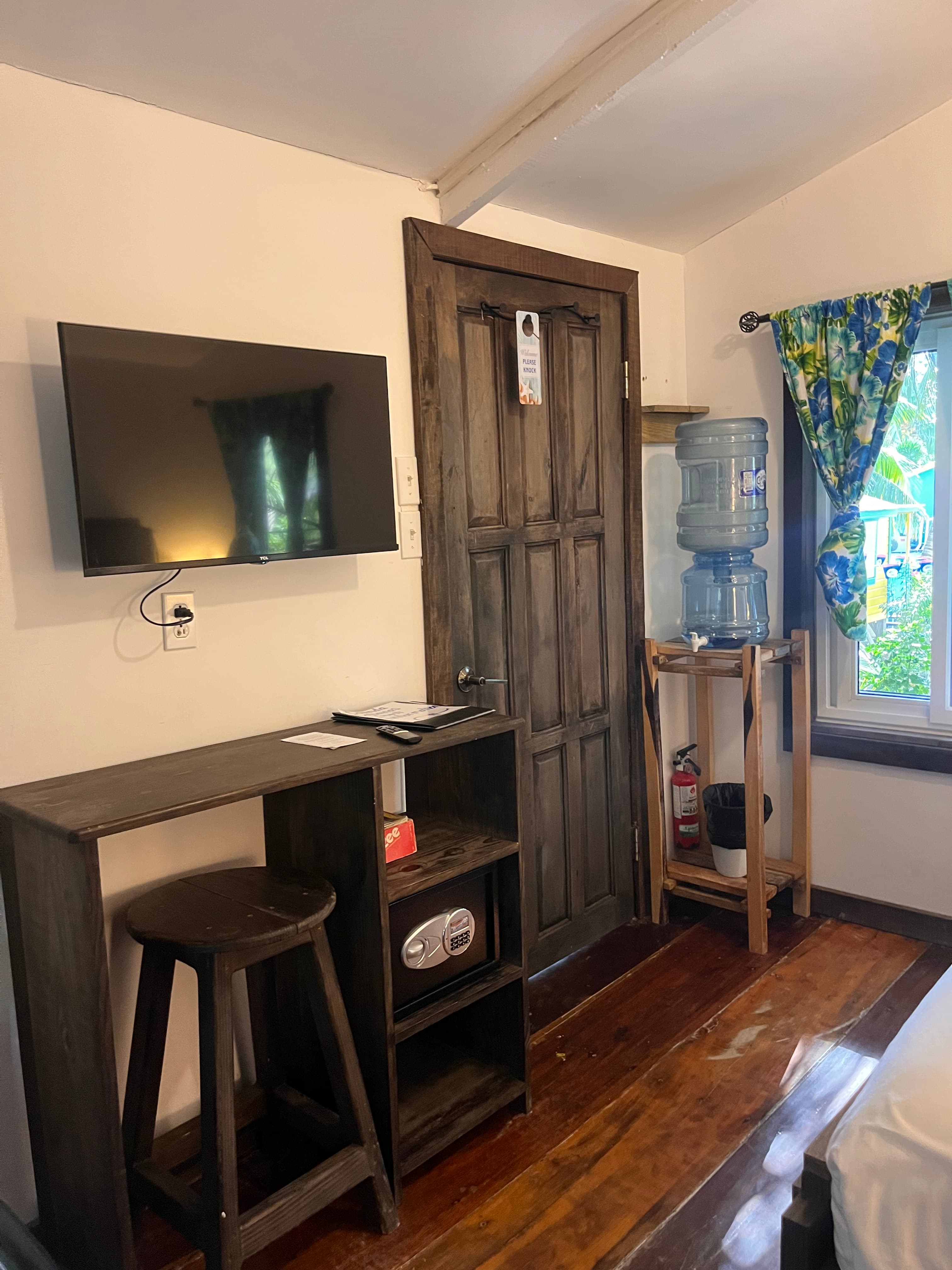 A cozy room featuring a wooden bar, a TV, a water dispenser, and a door leading outside.