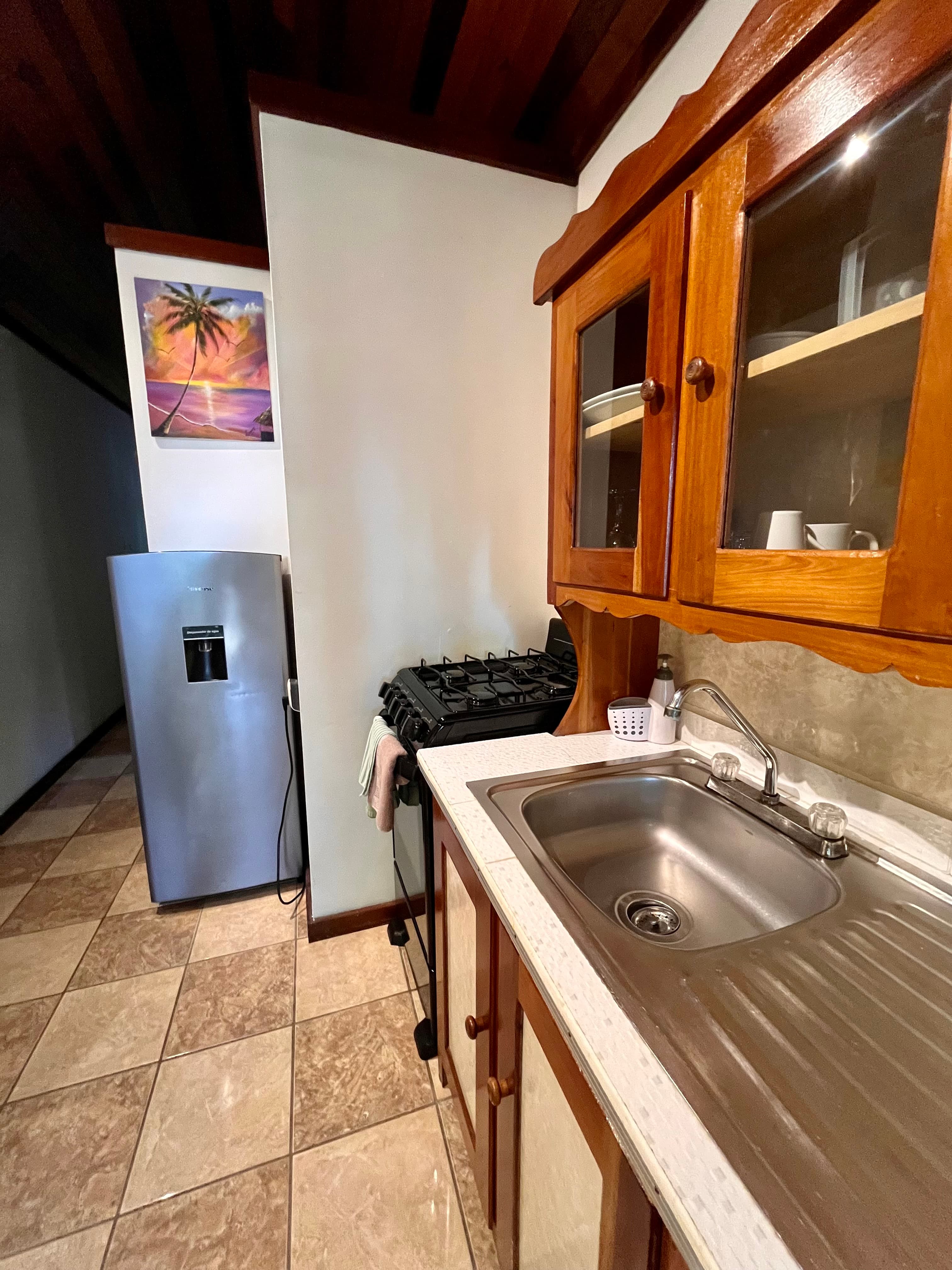 A kitchen featuring wooden cabinets, a stainless steel refrigerator, a gas stove, and a sink.