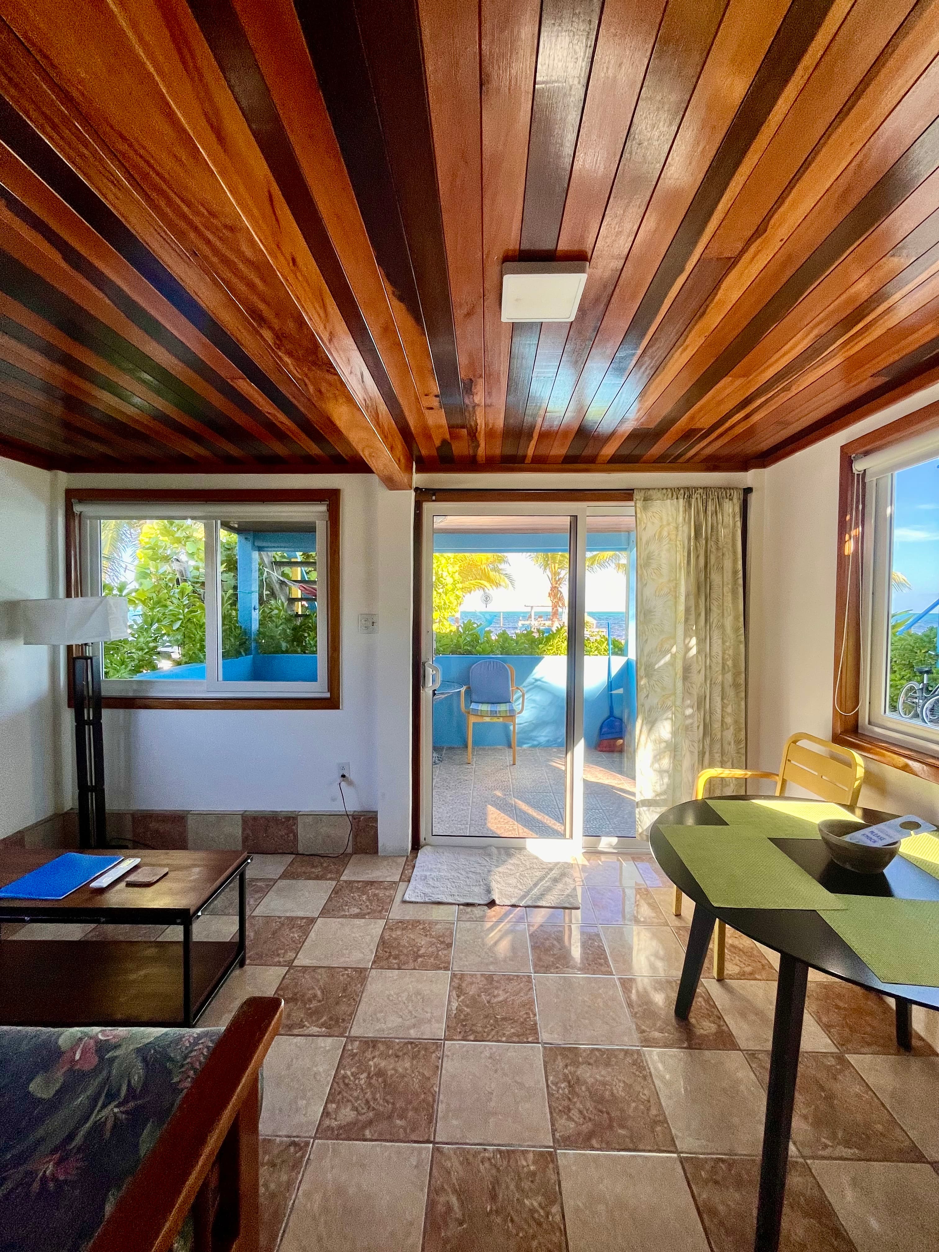 Cozy room with wooden ceiling, tiled floor, and a view of outdoor seating through sliding glass doors.