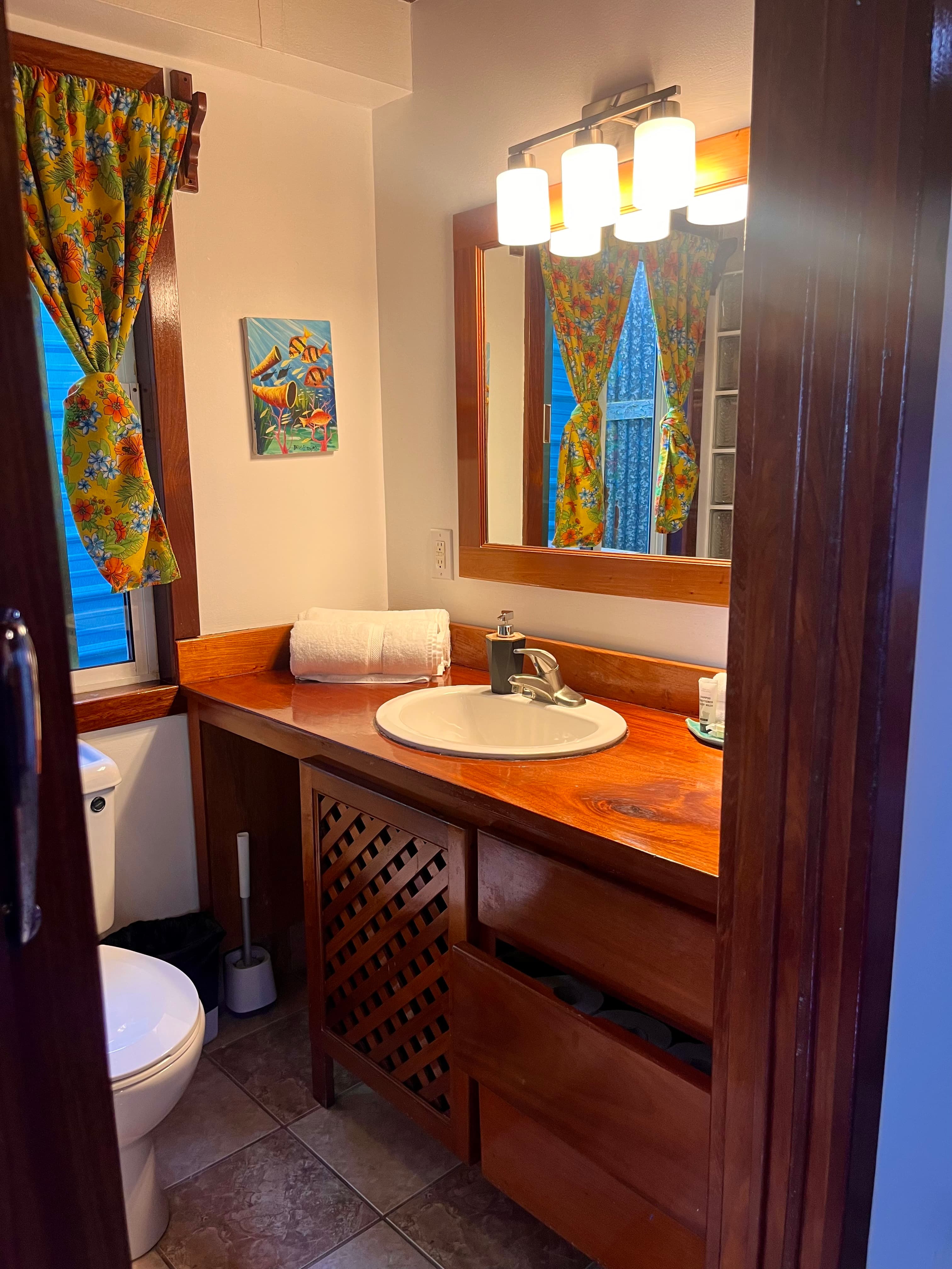 Brightly decorated bathroom with wooden accents, a round sink, and colorful curtains.