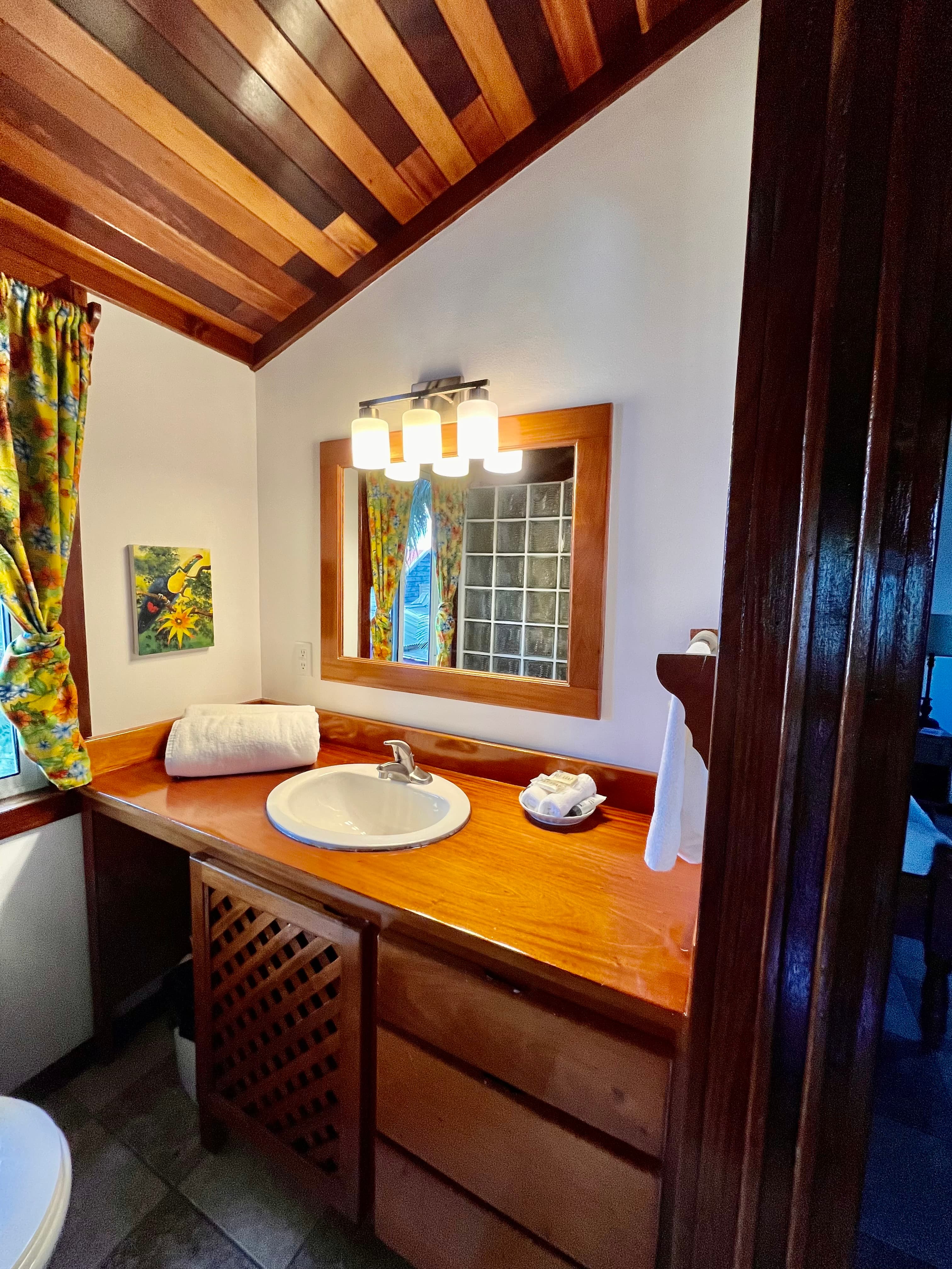 A cozy bathroom featuring wooden accents, colorful curtains, and a round sink.